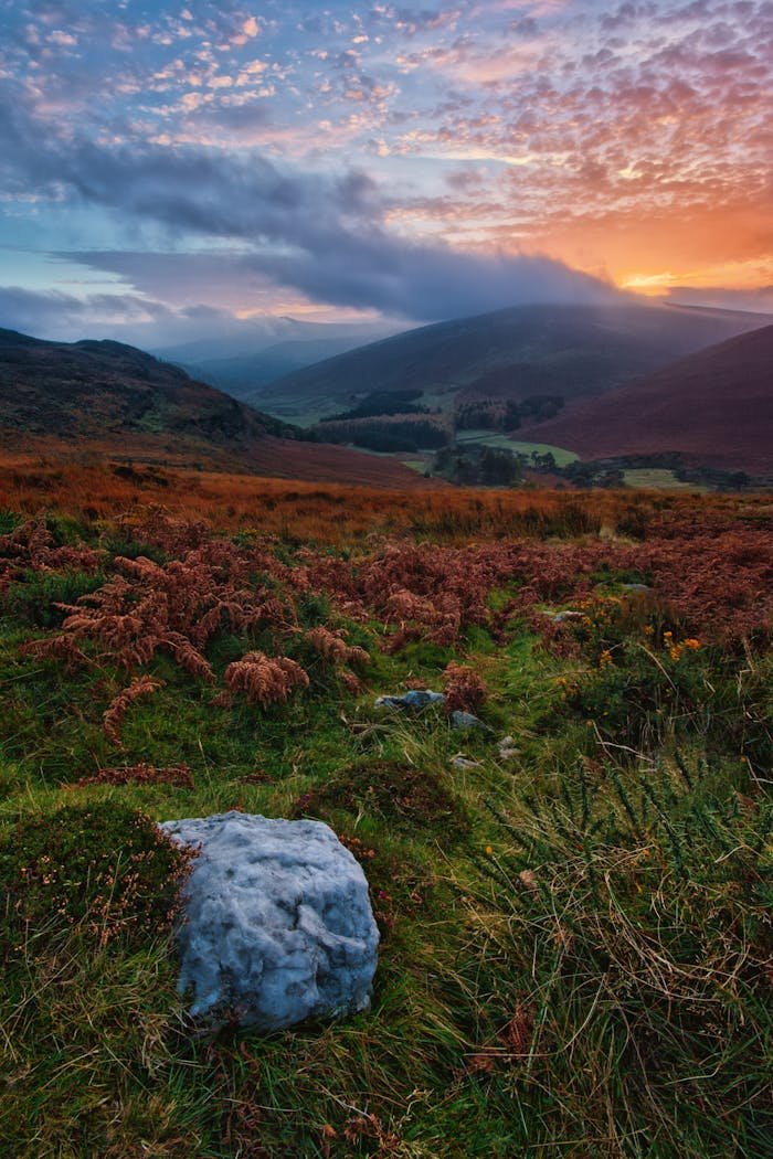 Serene Irish landscape with mountains and vibrant sunrise hues in the sky.