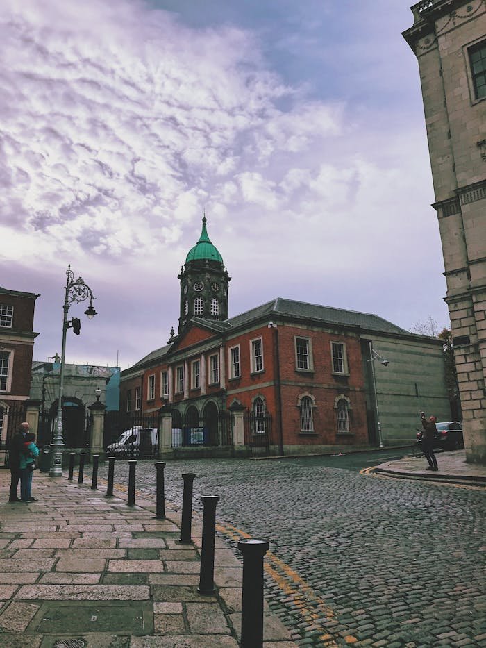 A scenic view of Dublin Castle courtyard with a focus on the historic clock tower under a cloudy sky.